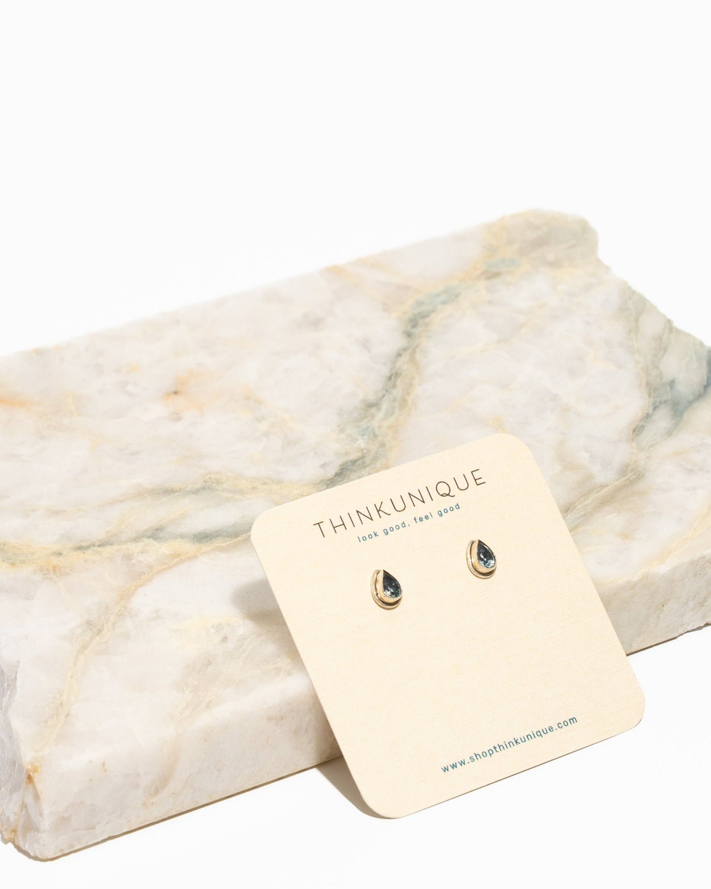 A pair of pear-shaped aquamarine stud earrings with sterling silver settings, displayed against a white background with a tag in front.