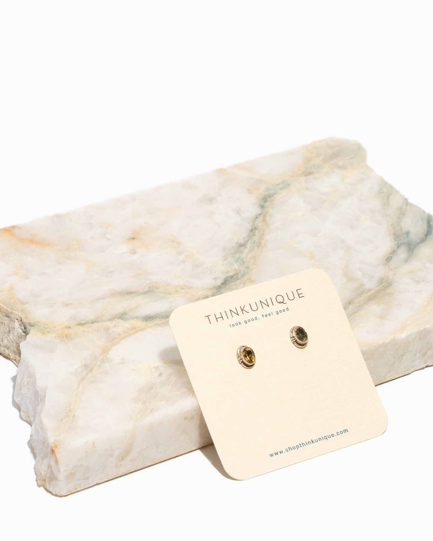 A pair of citrine oval stud earrings set in sterling silver, displayed on a white background with a tag in front.